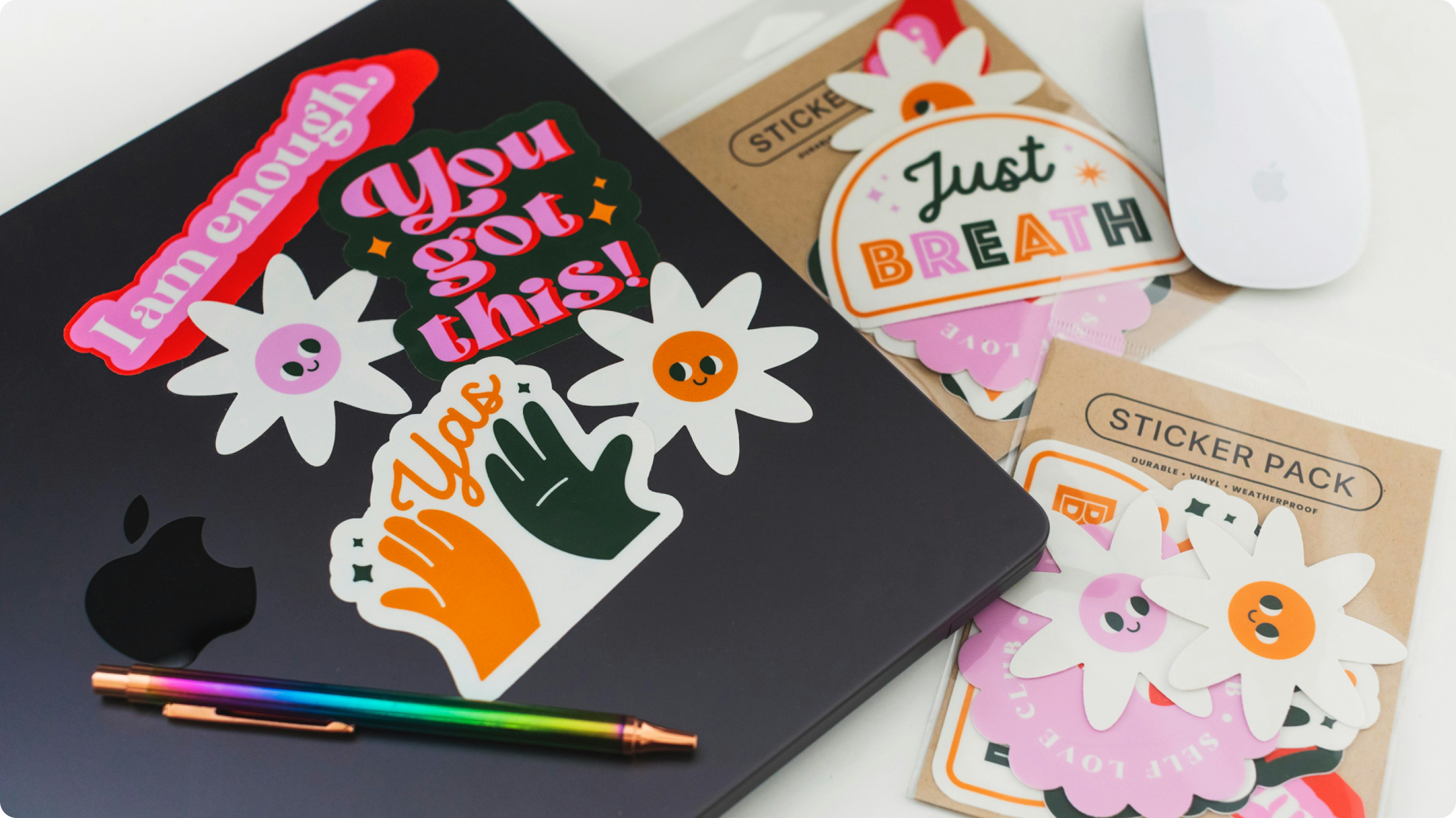 Colorful stickers on a laptop, sticker packs and desk accessories visible